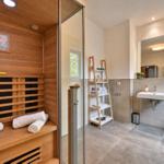 Dampfbad mit Holzverkleidung und Toilette im angrenzenden Badezimmer.