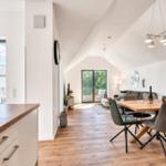 Wohn- und Essbereich mit Holzboden, Esszimmertisch und Schlafzimmer im Hintergrund.