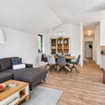 Wohn- und Essbereich mit Holzboden, Sofa, Tisch und Stühlen.