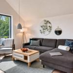 Wohnzimmer mit Sofa, Couchtisch und Blick auf Balkon mit Grün.
