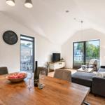 Ein Essbereich mit Holztisch, Sofa und TV. Durchgänge zu Terrasse und Garten.