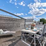 Terrasse mit Loungemöbeln und Esstisch unter blauem Himmel.