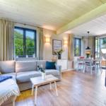 Living and dining area with sofa, table, and windows. Wooden ceiling and floor.