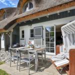 House with thatched roof, terrace with table, chairs, and beach chair.