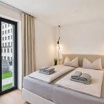 Schlafzimmer mit Doppelbett, Balkon und moderner Beleuchtung.