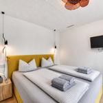 Schlafzimmer mit Doppelbett, gelbem Kopfteil, Fernseher und Nachttisch.