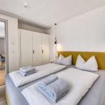 Schlafzimmer mit Bett, Kleiderschrank und Blick in angrenzenden Raum.