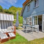 Blue wooden house with terrace, beach chair, and outdoor dining table.