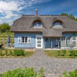 Blue house with thatched roof and garden area with sun loungers.
