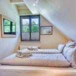 Bedroom with sloped ceiling, bed with checkered bedding, and window with view of trees.