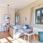 Wohn- und Essbereich mit Sofa, Tisch und Fensterblick auf Dächer.
