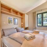 Schlafzimmer mit Doppelbett, Holzmöbeln und Fensterblick auf Garten.
