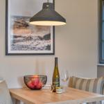 Esstisch mit Stühlen, Weinflasche und Obstschale unter einer Lampe.
