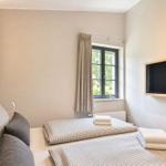 Zimmer mit zwei Betten, Fenster und Wandfernseher.