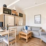 Wohn- und Essbereich mit Küchenzeile, Sofa und Stühlen. Holzmöbel und Wandbild.