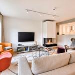 Wohnzimmer mit Sofa, Sesseln und Kamin. Fernseher und Wohnbereich sind sichtbar.