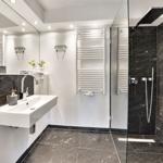Badezimmer mit Dusche, Waschbecken und Heizkörper.