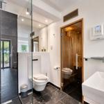 Badezimmer mit Dusche, Toilette und Sauna. Schwarze Fliesen und weiße Wand.