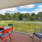 Terrasse mit Tisch, Stühlen und Blick auf Pool und Wald.