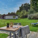 Garten mit Tisch, Stühlen und Liege. Im Hintergrund das Haus und Bäume.
