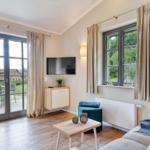 Wohnzimmer mit Sofa, Couchtisch, Fernseher und Fenster zur Terrasse.