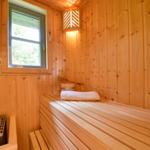Sauna mit Holzwand, Fenster, Holzbank und Handtuch.