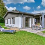 Moderne Ferienhaus mit Terrasse, Gartenliege und Sitzgelegenheit unter freiem Himmel.