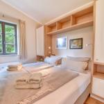 Schlafzimmer mit Doppelbett, Fenster mit Blick auf Bäume und integrierte Schränke.
