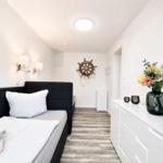 Bedroom with bed, dresser, and ships wheel on the wall.