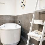 Bath with freestanding bathtub, shower head, towel rack, and white ladder shelf.