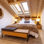 Schlafzimmer mit Dachboden, Holzdecke, Fenster und Bett mit Felldecke.