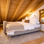 Schlafzimmer mit Holzdecke, Bett, Spiegel und Teppich.