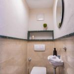 Badezimmer mit Toilette, Waschbecken und runden Spiegel an der Wand.