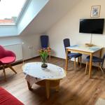 Wohnzimmer mit Dachfenster, Esstisch, TV und rotem Sessel.