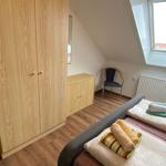 Schlafzimmer mit Dachschrägen, Bett, Kleiderschrank und Stuhl.