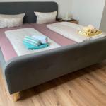 Doppelbett mit rosa Matratzen und gefalteten Handtüchern auf Holzboden.