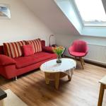 Wohnzimmer mit rotem Sofa, Stuhl und Tisch unter Dachfenster.