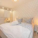 Bedroom with bed, nightstand, and wardrobe. Wall with pattern. Ceiling light and table lamp.