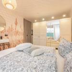 Bedroom with bed, wardrobe, and sink against wall with plant pattern.