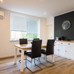 Dining room with table, chairs, window, and cabinet against black wall.