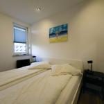 Bedroom with bed, nightstand, and wall art. Window with blinds.
