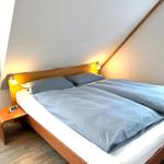 Ein Schlafzimmer mit Doppelbett, Holzrahmen und Fenster.
