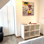 Schlafzimmer mit weißem Schrank, Bett und Regal. Wandbild zeigt einen Hund auf Motorrad.