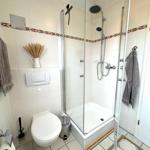 Badezimmer mit Dusche, Toilette und Handtuchhalter. Fliesen mit dekorativer Bordüre.