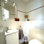 Badezimmer mit Waschbecken, Spiegel, Toilette und Handtuchhalter.