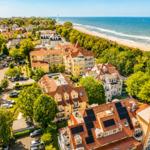 Luftbild von Hotels und Häusern am Strand mit Blick aufs Meer und einen Fahrradweg.