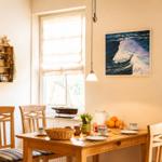 Esszimmer mit Holztisch, Stühlen und Seemotiven an der Wand.