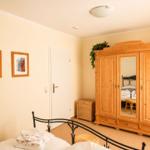 Schlafzimmer mit Holzschrank, Bett und Wandbildern.
