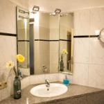 Badezimmer mit Waschbecken, Spiegeln und Blumen in Vase