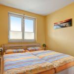 Schlafzimmer mit Doppelbett, Fenster und Wandbild.